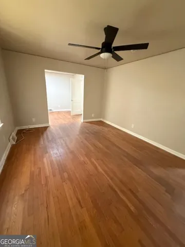an empty room with wooden floor fan and windows