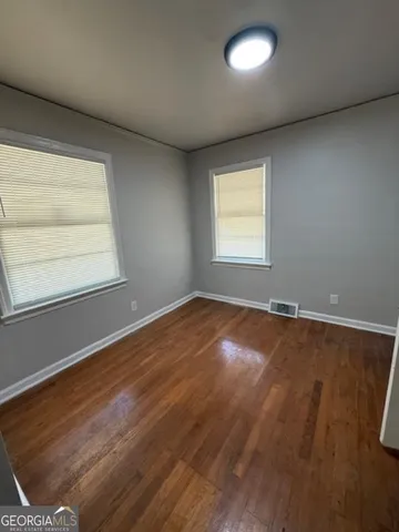 an empty room with wooden floor and windows