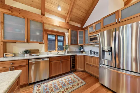 a kitchen with stainless steel appliances granite countertop a refrigerator a sink dishwasher a stove and white countertops with wooden floor