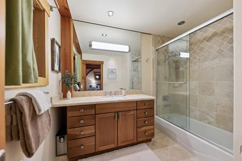 a bathroom with a double vanity sink a large mirror and a bathtub