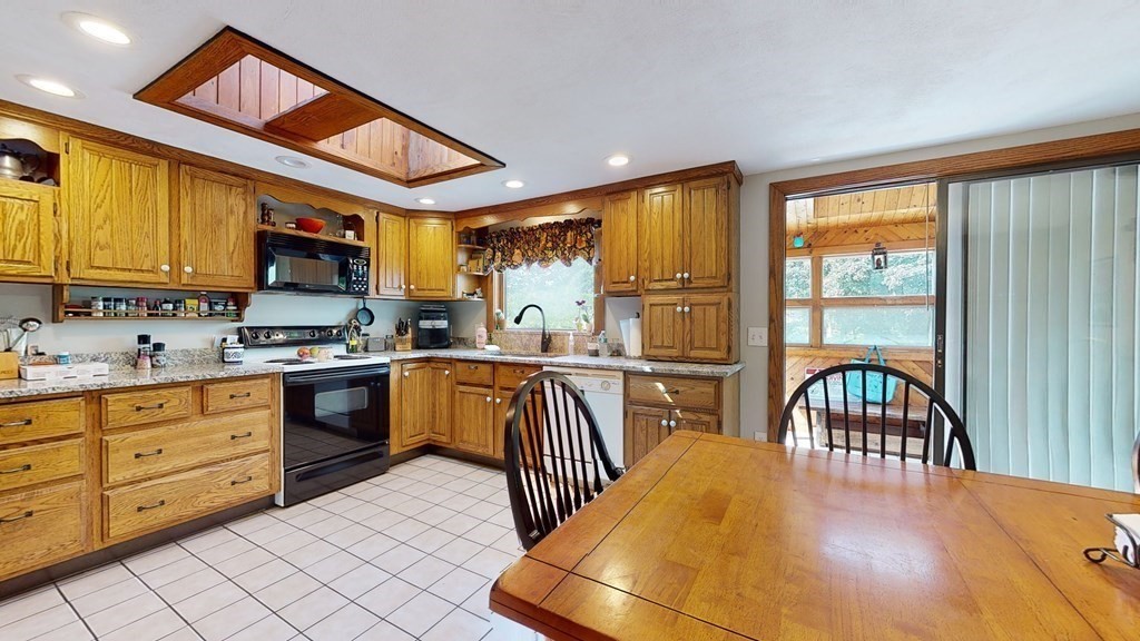 25 Charlton Road Dudley, MA 01571 - Photo 15 of 42 a kitchen with stainless steel appliances granite countertop a stove a sink a dining table and chairs with wooden floor