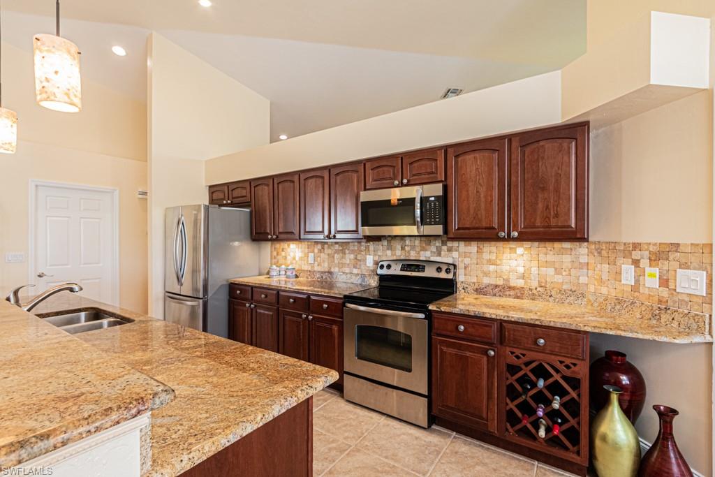 248 St James Way Naples, FL 34104 - Photo 11 of 34 a kitchen with stainless steel appliances granite countertop a stove top oven a sink dishwasher and wooden cabinets with wooden floor