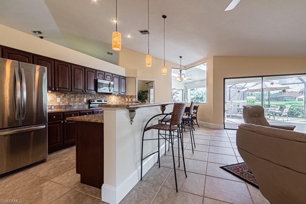 248 St James Way Naples, FL 34104 - Photo 6 of 34 a kitchen with stainless steel appliances granite countertop a refrigerator a stove a sink a dining table and chairs with wooden floor