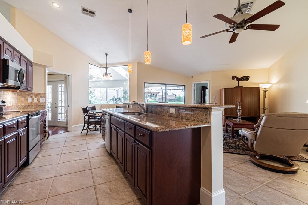 248 St James Way Naples, FL 34104 - Photo 7 of 34 a kitchen with stainless steel appliances granite countertop a stove top oven a sink dishwasher a dining table and chairs with wooden floor