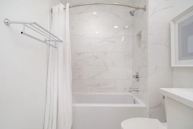 a bathroom with a shower a toilet and bathtub