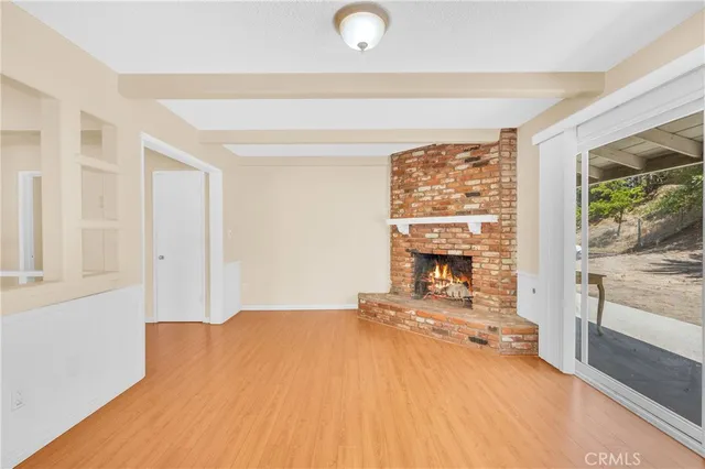 a view of an empty room with a window and a fireplace