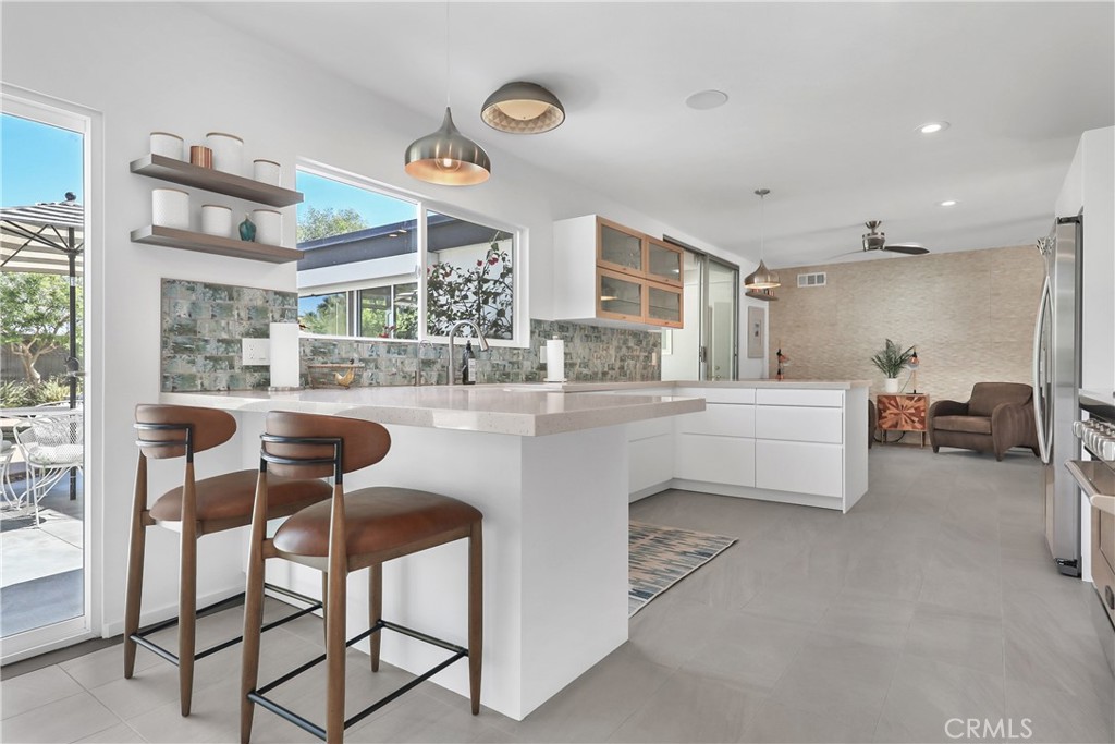 71620 Halgar Road Rancho Mirage, CA 92270 - Photo 15 of 41 a kitchen with stainless steel appliances kitchen island granite countertop a table chairs sink and cabinets