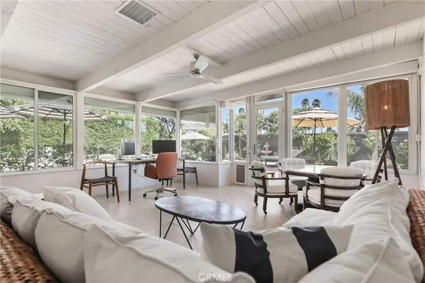 a living room with furniture large windows and wooden floor