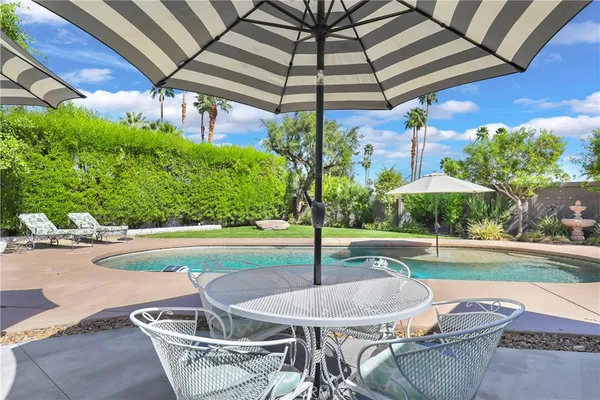 a patio with a table and chairs under an umbrella