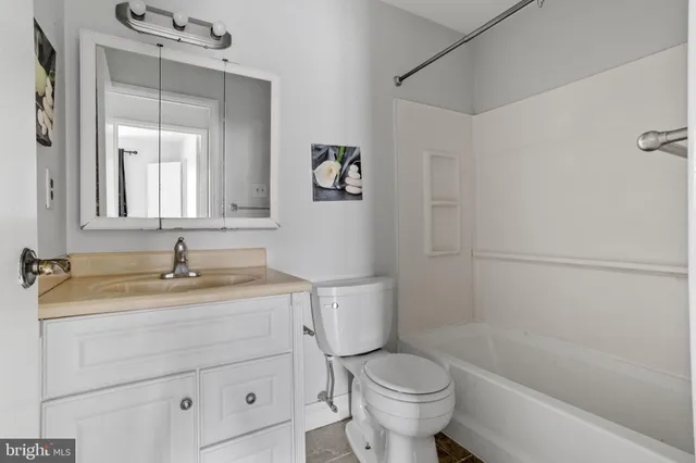 a bathroom with a granite countertop sink a toilet and bathtub