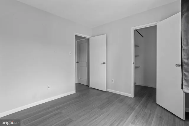 a view of an empty room with wooden floor and closet