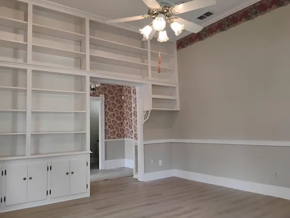 a view of an empty room with a window and wooden floor