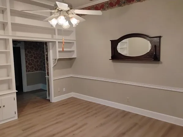 an empty room with wooden floor cabinet and windows