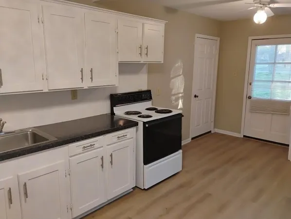 a kitchen with granite countertop white cabinets and white appliances