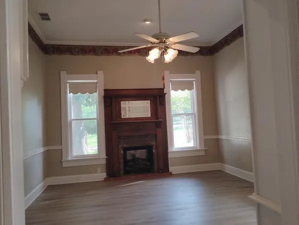 an empty room with wooden floor fireplace and windows