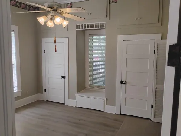 an empty room with wooden floor closet and windows