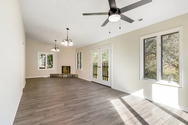 a view of an empty room with a window and wooden floor