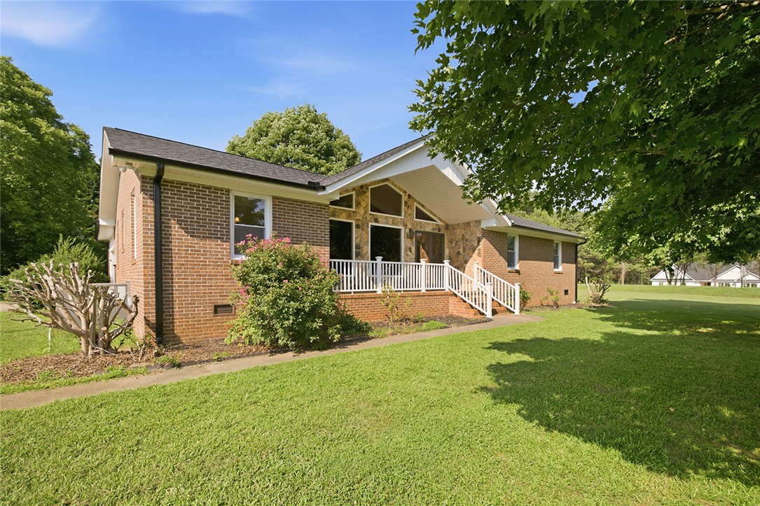 902 Cherokee Road Pelzer, SC 29669 - Photo 20 of 38 A well-maintained brick and stone façade welcomes you to this verdant property.