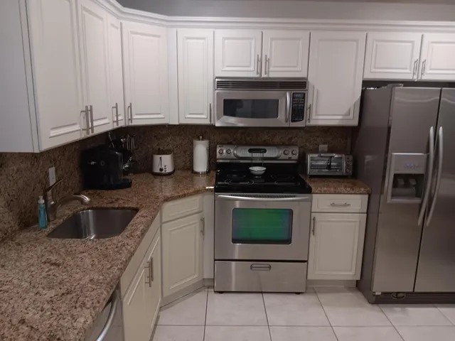 a kitchen with granite countertop a sink and a refrigerator