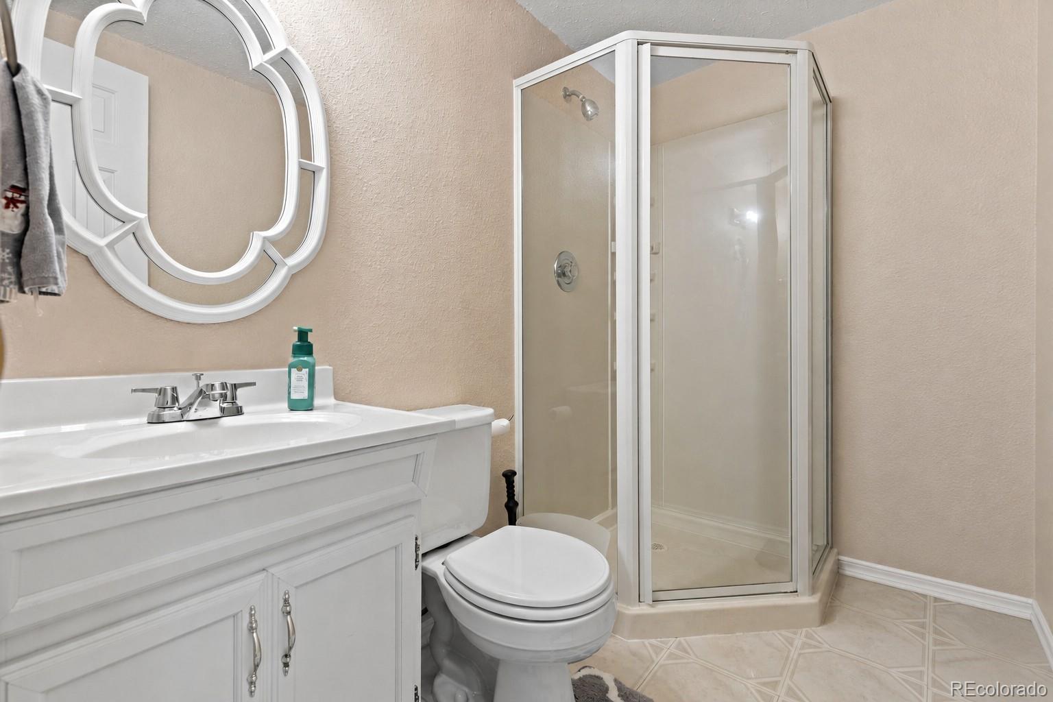 10565 Hyacinth Place Highlands Ranch, CO 80129 - Photo 27 of 33 a bathroom with a granite countertop toilet a sink and a mirror