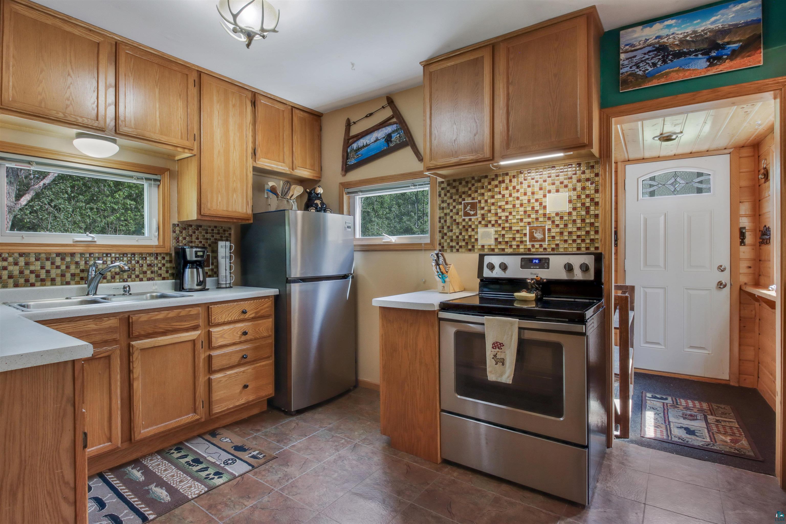 N8348 Island Lake Road Spooner, WI 54801 - Photo 15 of 40 Kitchen with sink, tasteful backsplash, dark tile patterned flooring, and stainless steel appliances