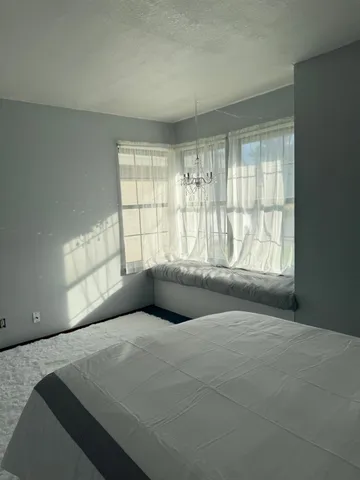 a bedroom with a bed and a large window