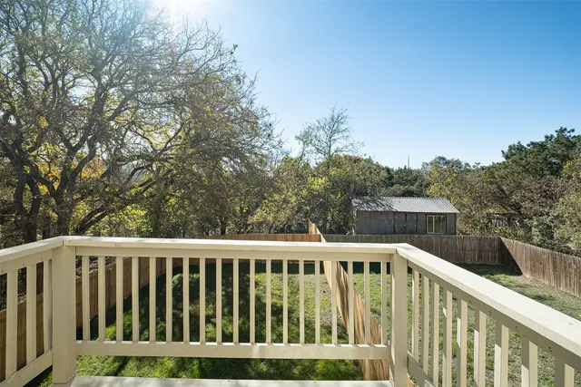 a balcony with wooden floor and trees in the background