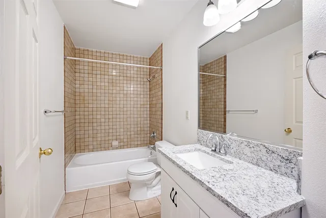 a bathroom with a granite countertop sink a toilet a mirror and shower