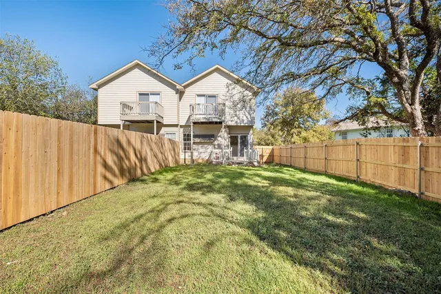 a view of backyard of house with wooden fence