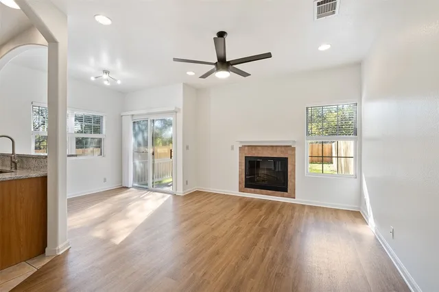 a view of an empty room with window and wooden floor