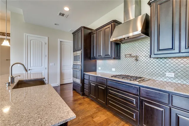 a kitchen with stainless steel appliances granite countertop a stove a sink and a refrigerator