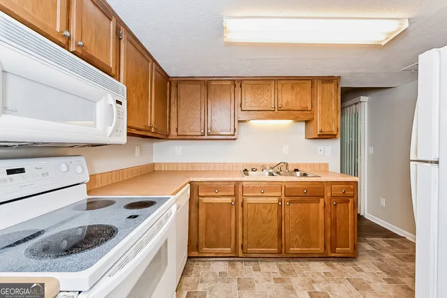a kitchen with granite countertop a sink a stove and cabinets