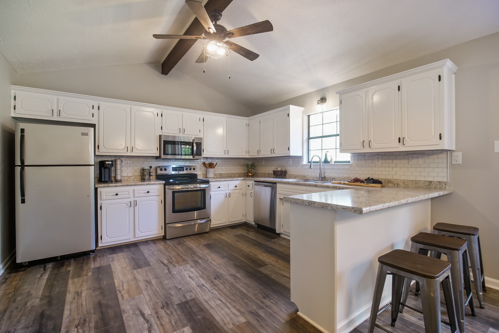 3977 Cairo Bend Road Lebanon, TN 37087 - Photo 19 of 39 a kitchen with granite countertop wooden floors stainless steel appliances and white cabinets