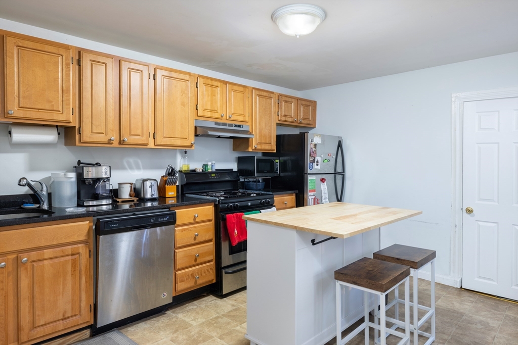 140 Athens Street Boston, MA 02127 - Photo 11 of 11 a kitchen with a stove a sink dishwasher and white cabinets with wooden floor