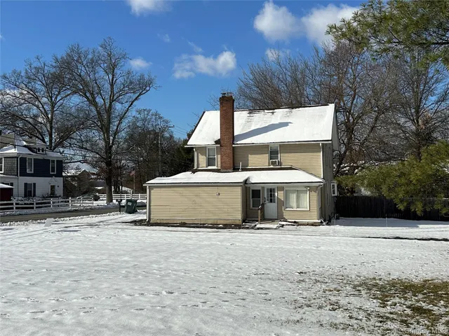 a view of a white house with a yard covered in snow