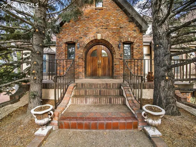 a view of a brick house with large windows and a table and chairs