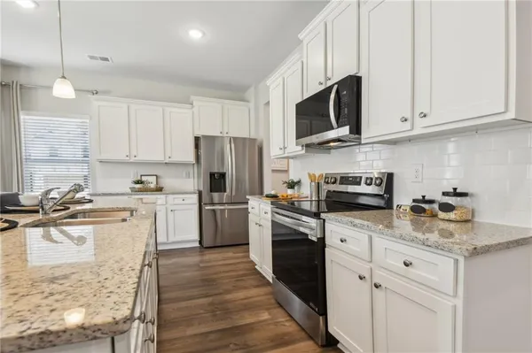 a kitchen with a sink a microwave a refrigerator and cabinets