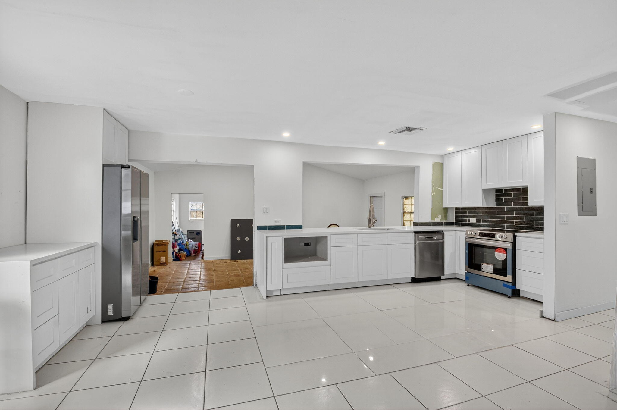 5196 Palm Ridge Boulevard Delray Beach, FL 33484 - Photo 5 of 24 a large white kitchen with stainless steel appliances kitchen island granite countertop a large counter top and a stove top oven