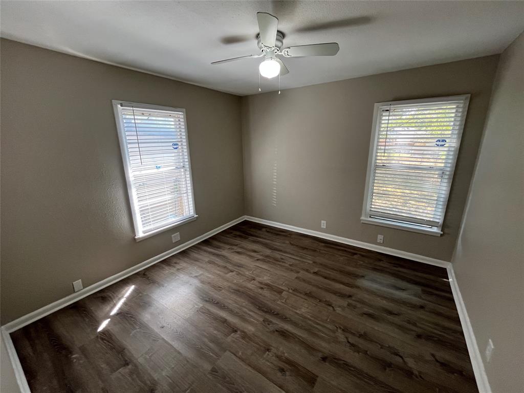 1622 Centerville Road Dallas, TX 75228 - Photo 17 of 19 Wood-finish flooring, neutral wall tones, white trim, two windows with blinds, and a ceiling fan with integrated lighting