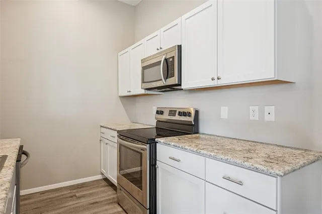 a kitchen with granite countertop cabinets stainless steel appliances and wooden floor