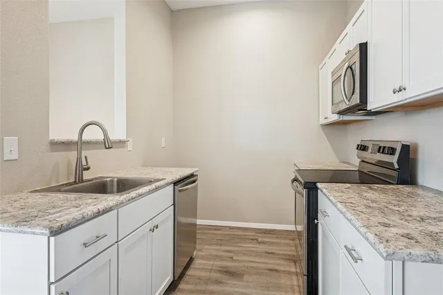 a kitchen with granite countertop cabinets stainless steel appliances and a sink