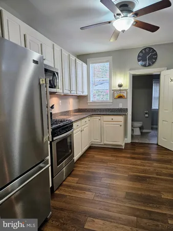 a kitchen with stainless steel appliances a refrigerator a stove a sink and white cabinets with wooden floor