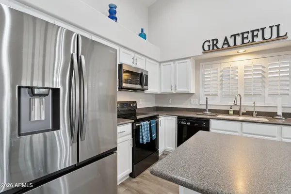 a kitchen with stainless steel appliances granite countertop a refrigerator a stove a sink and a microwave