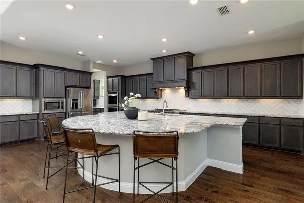 a kitchen with kitchen island granite countertop wooden cabinets and stainless steel appliances