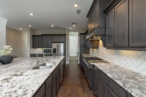 a kitchen with stainless steel appliances granite countertop sink stove refrigerator and cabinets