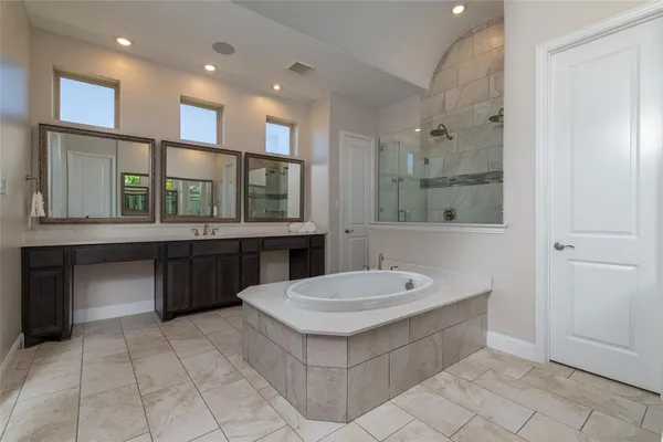 a bathroom with a double vanity sink mirror and bathtub