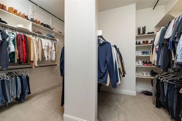 a view of walk in closet with clothes and shoes