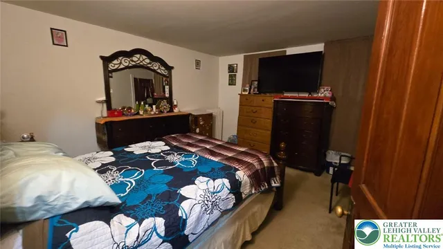 a bedroom with bed and a flat tv screen on a dresser