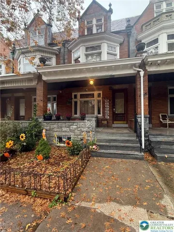 a front view of a building with lots of trees and plants