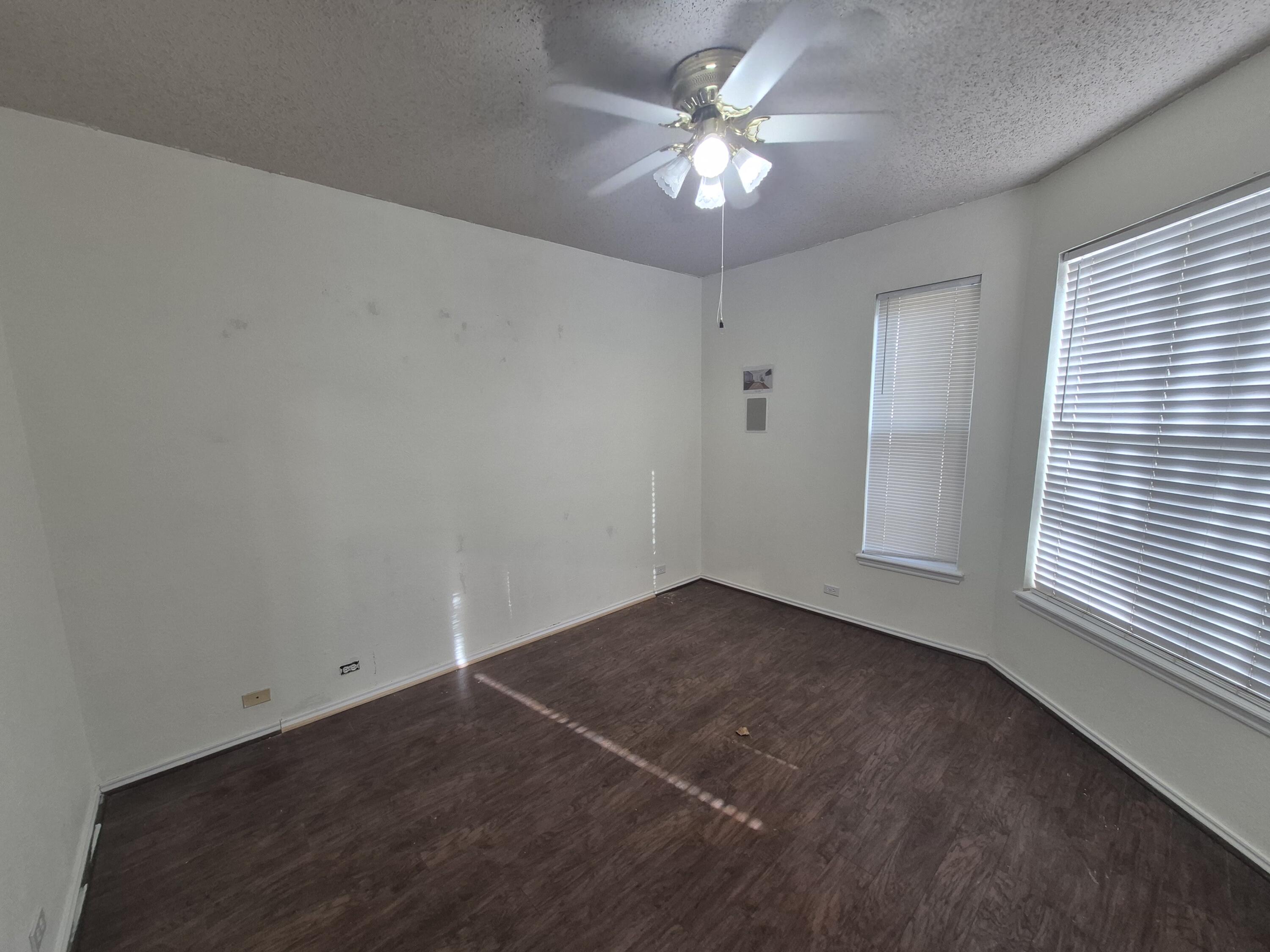 5117 79th Drive Lubbock, TX 79424 - Photo 13 of 35 an empty room with a chandelier fan and windows